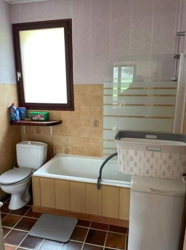 Un baño con inodoro, bañera y zona de ducha.