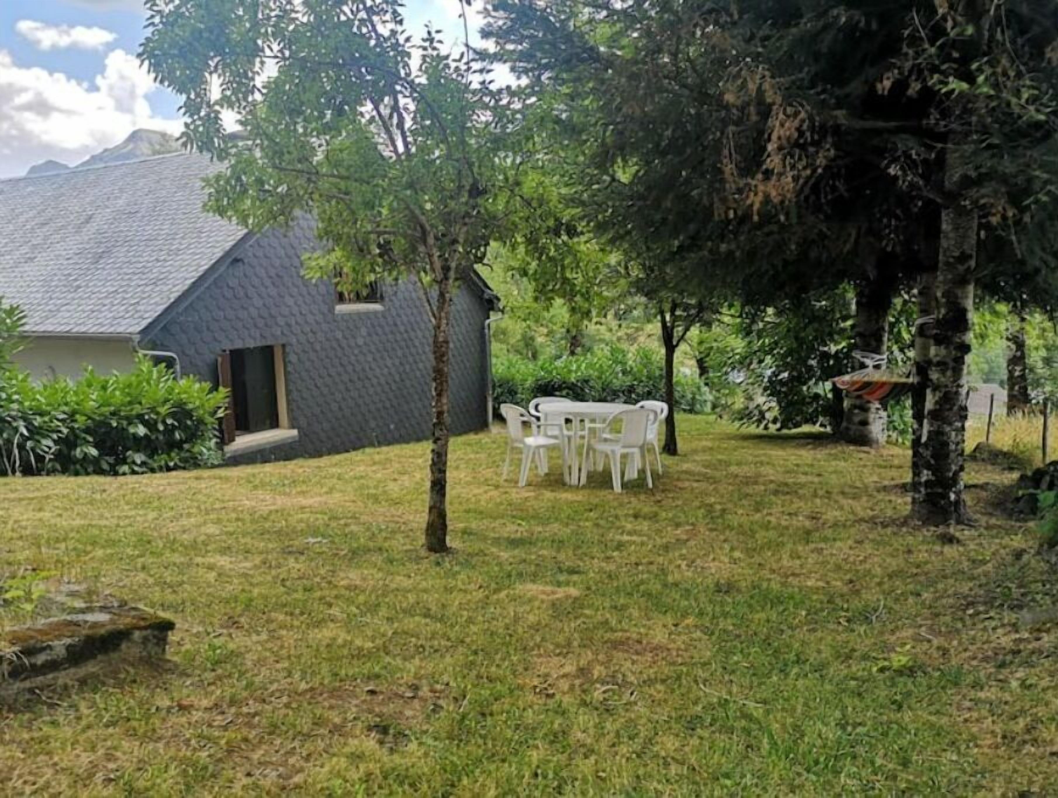 A house with a sloped roof, a small porch, and a grassy yard with a white table and chairs.
