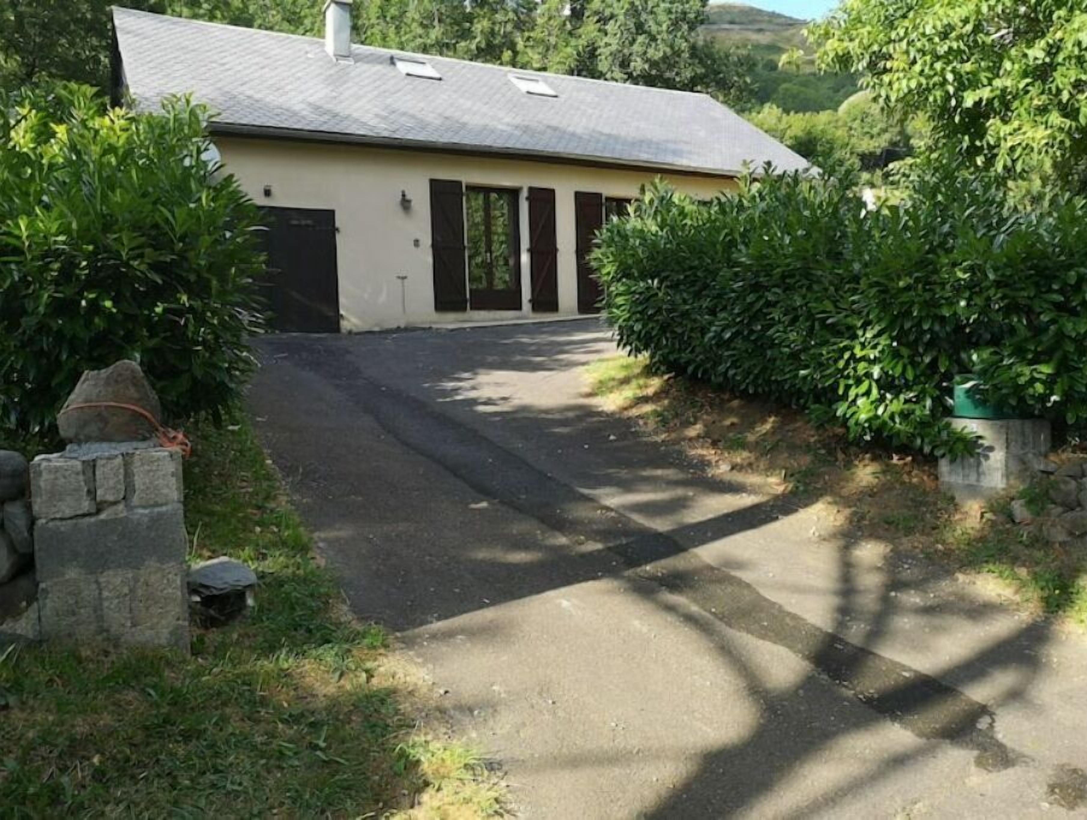 Una casa con un camino de entrada pavimentado que lleva a un garaje.
