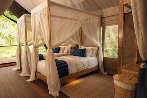 A four-poster canopy bed with a wooden frame, white bedding, and blue accent pillows. - Visama Explorer Nan (Bo Kluea)