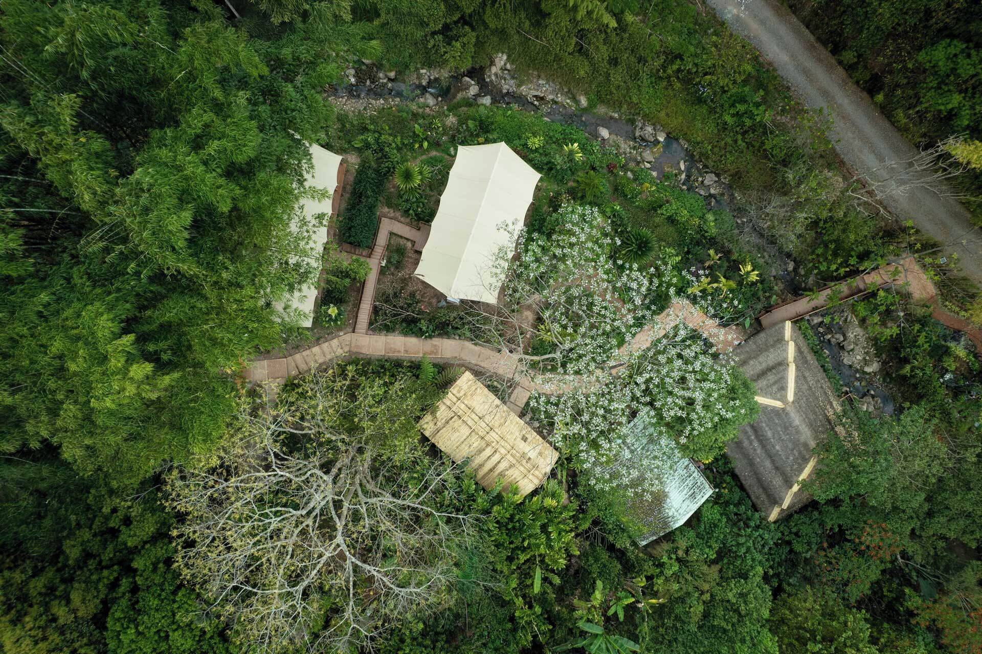 Luchtbeeld van een pand met een geplaveid pad, een klein gebouw en weelderige begroeiing.