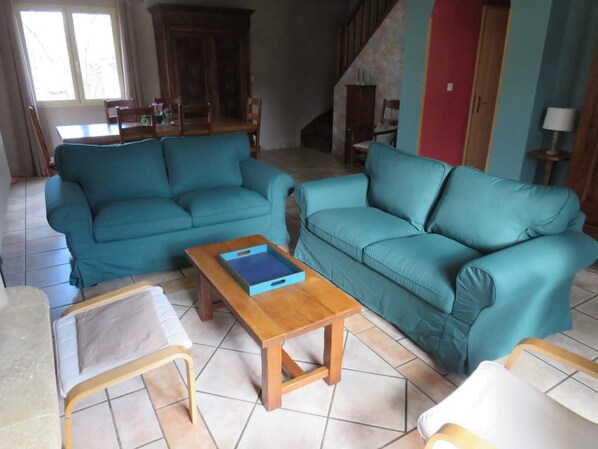Una sala de estar con dos sofás turquesa, una mesa de centro de madera y una pequeña mesa blanca.