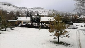 A snow-covered landscape with a house and a mountain in the background.