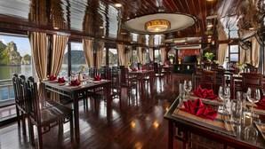 A restaurant with wooden floors and tables set for dining, large windows with curtains, and a view of a lake. - La Regina Classic Cruise (Bai Chay)