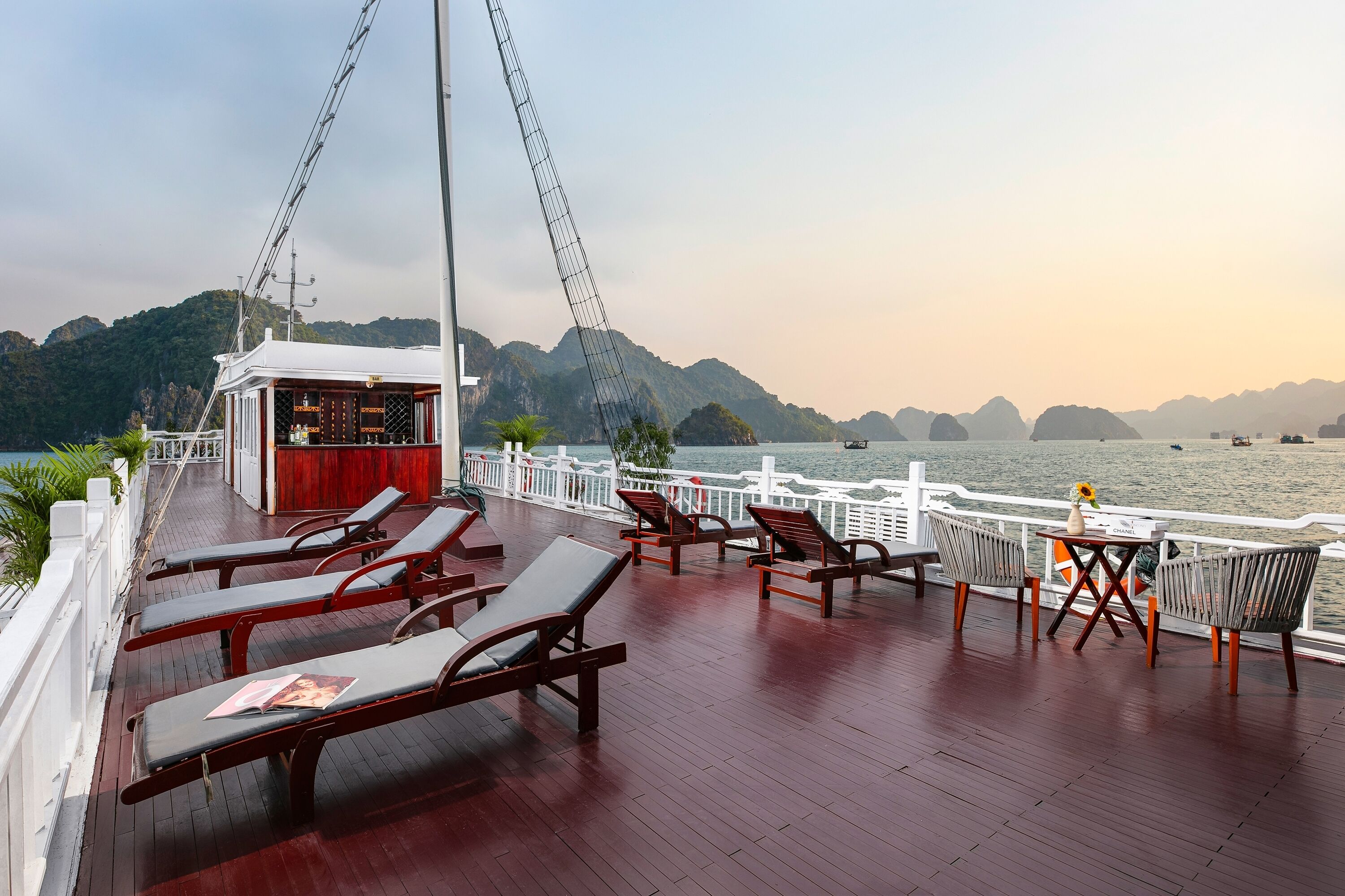 A deck with sun loungers, a bar, and a view of the water.