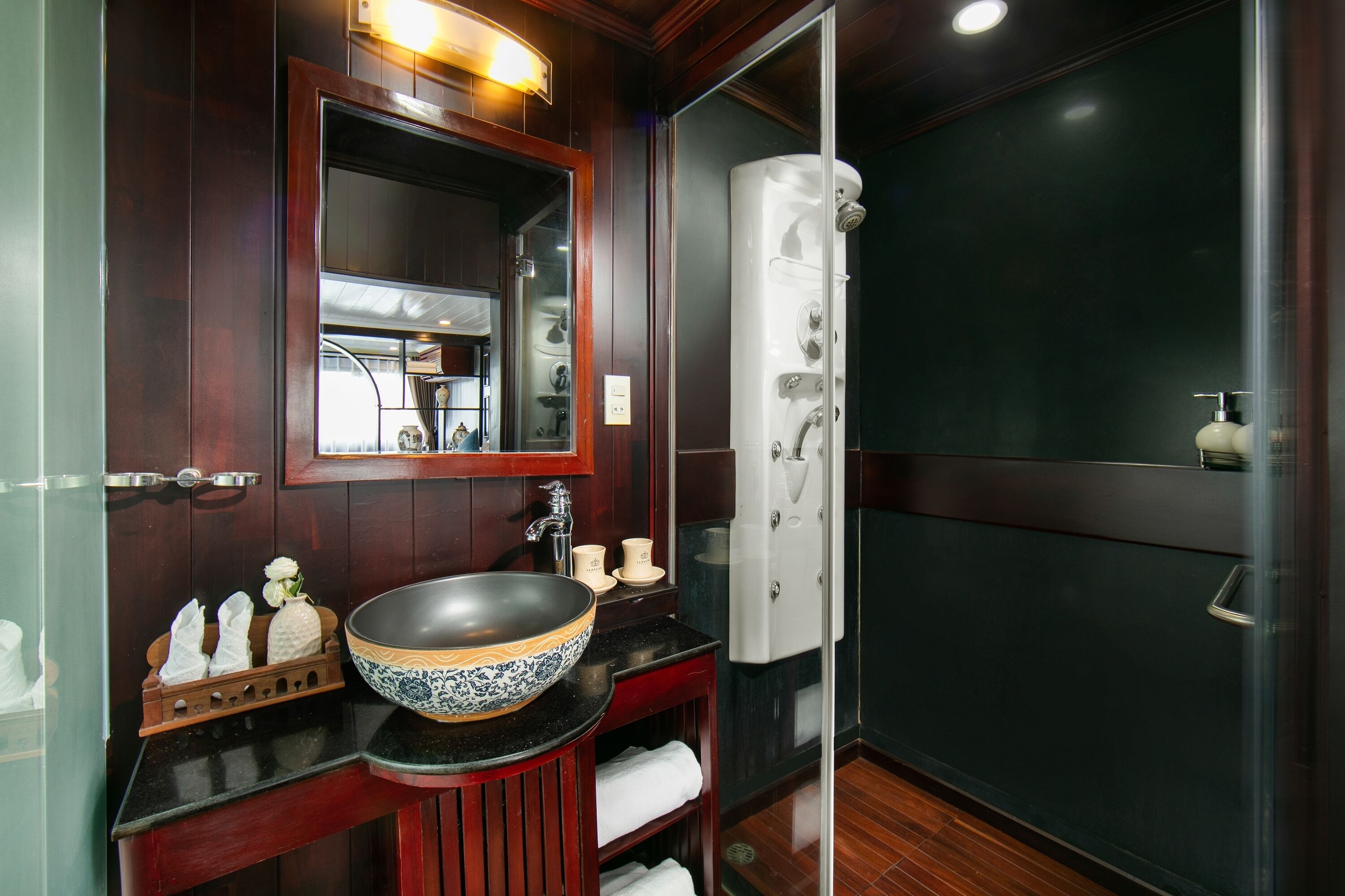 A bathroom with a large mirror, a vessel sink, and a walk-in shower.