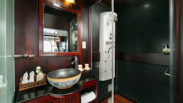 A bathroom with a large mirror, a vessel sink, and a walk-in shower.