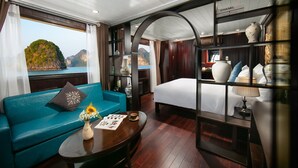 A room with a sofa, a bed, a coffee table, and a view of the sea. - La Regina Classic Cruise (Bai Chay)