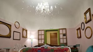 A room with a bed, a chair, a table, a chandelier, and a door. - Cialoma B&B (Palermo)