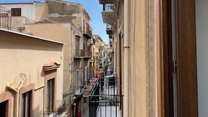 A narrow urban street with multi-story buildings, balconies, and a clear sky. - Cialoma B&B (Palermo)