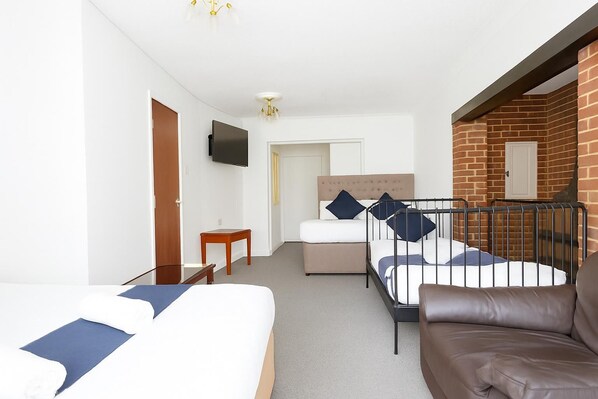 A hotel room with two beds, a TV, a small table, and a couch. - All Seasons Gatwick Guest House (Horley)