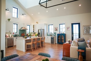 A spacious kitchen with wooden chairs, a dining table, and a living area with a sofa and a coffee table.