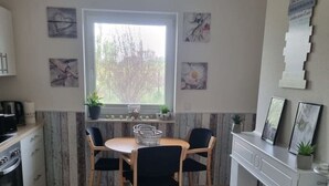 Une cuisine compacte comprenant une table à manger, des chaises, un four encastré et une fenêtre.