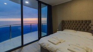 Una habitación de hotel con una cama grande, vistas al mar y un balcón con puertas de cristal.