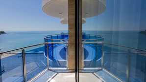 Barandilla de cristal con vistas a una piscina y al mar.