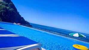 Una piscina azul cristalina con vistas al océano y un acantilado rocoso.