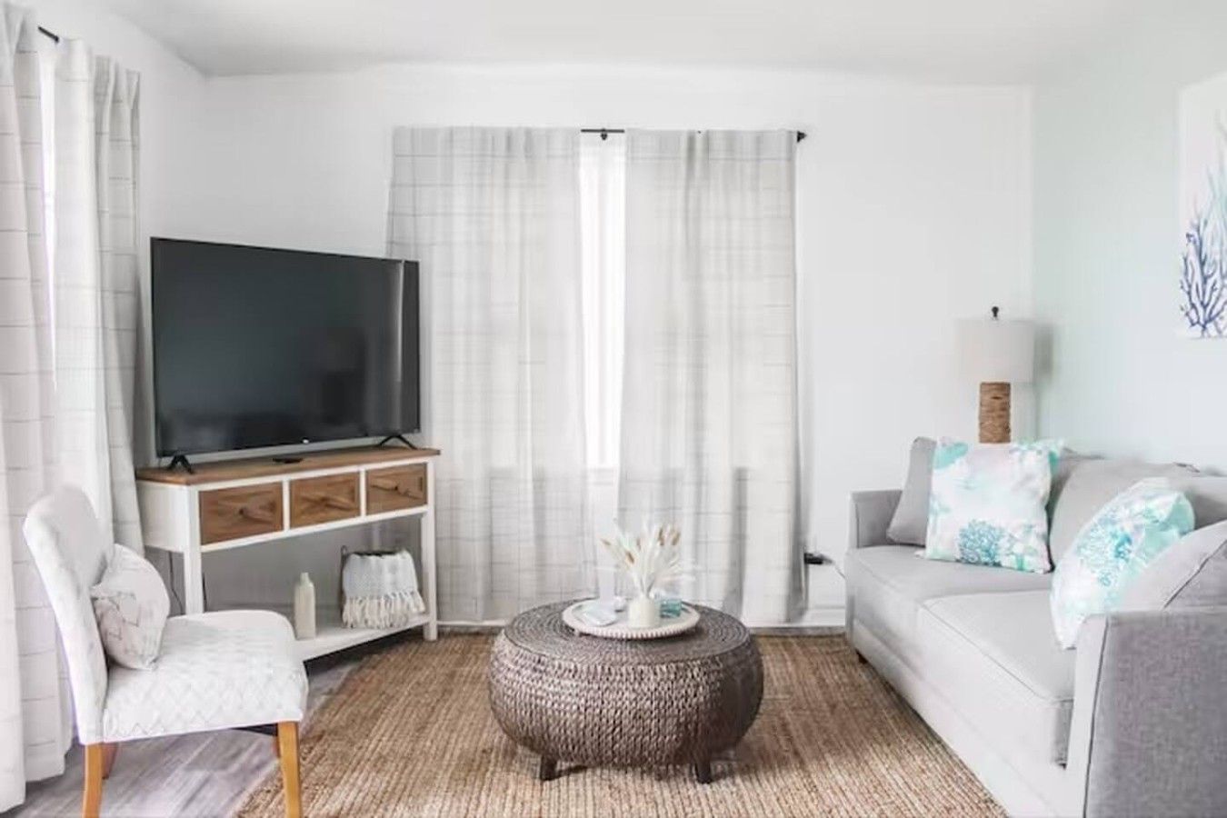 Una sala de estar con televisor de pantalla plana, sofá, sillón y una mesa de centro redonda.