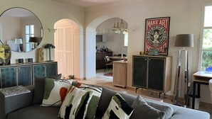 Ein modernes Wohnzimmer mit grauem Sofa, Couchtisch und Essbereich im Hintergrund.