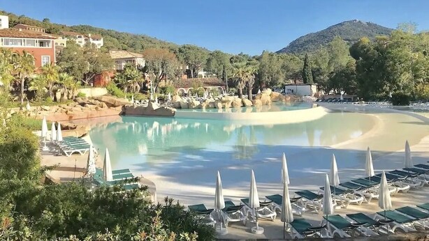 Ein Resort mit großem Pool, Liegestühlen und einer Bergkulisse.
