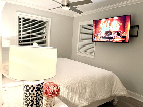 Ein Schlafzimmer mit einem Bett, einem Fernseher, der ein Feuer zeigt, und einer Lampe.
