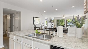 A modern kitchen with white cabinetry, a double sink, and a dishwasher. - Dream Condo with Perfect Location for All The Fun! (Osage Beach)