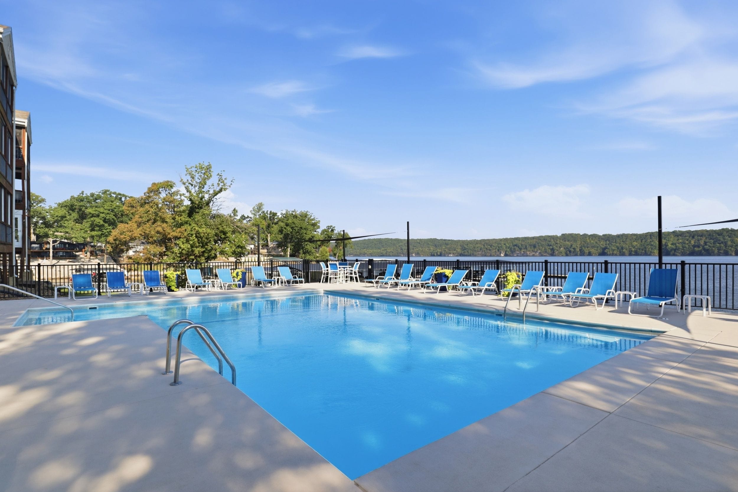 Une piscine avec des chaises bleues et une vue sur un lac.