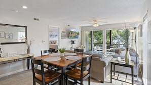 A modern kitchen with a dining table, chairs, and a large window overlooking a garden. - Dream Condo with Perfect Location for All The Fun! (Osage Beach)