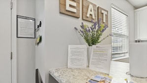 A reception area with a marble counter, framed documents, a vase with lavender, and a window with blinds. - Dream Condo with Perfect Location for All The Fun! (Osage Beach)