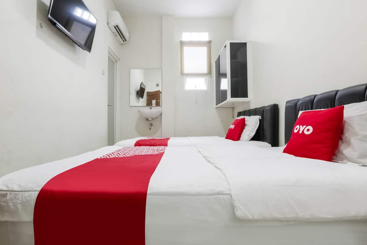 Hotellihuone, jossa on sänky, seinälle asennettu televisio, ikkuna ja peili.