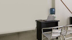 Een kamer met een bureau, een stoel, een waterdispenser en een bezem die tegen de muur leunt.
