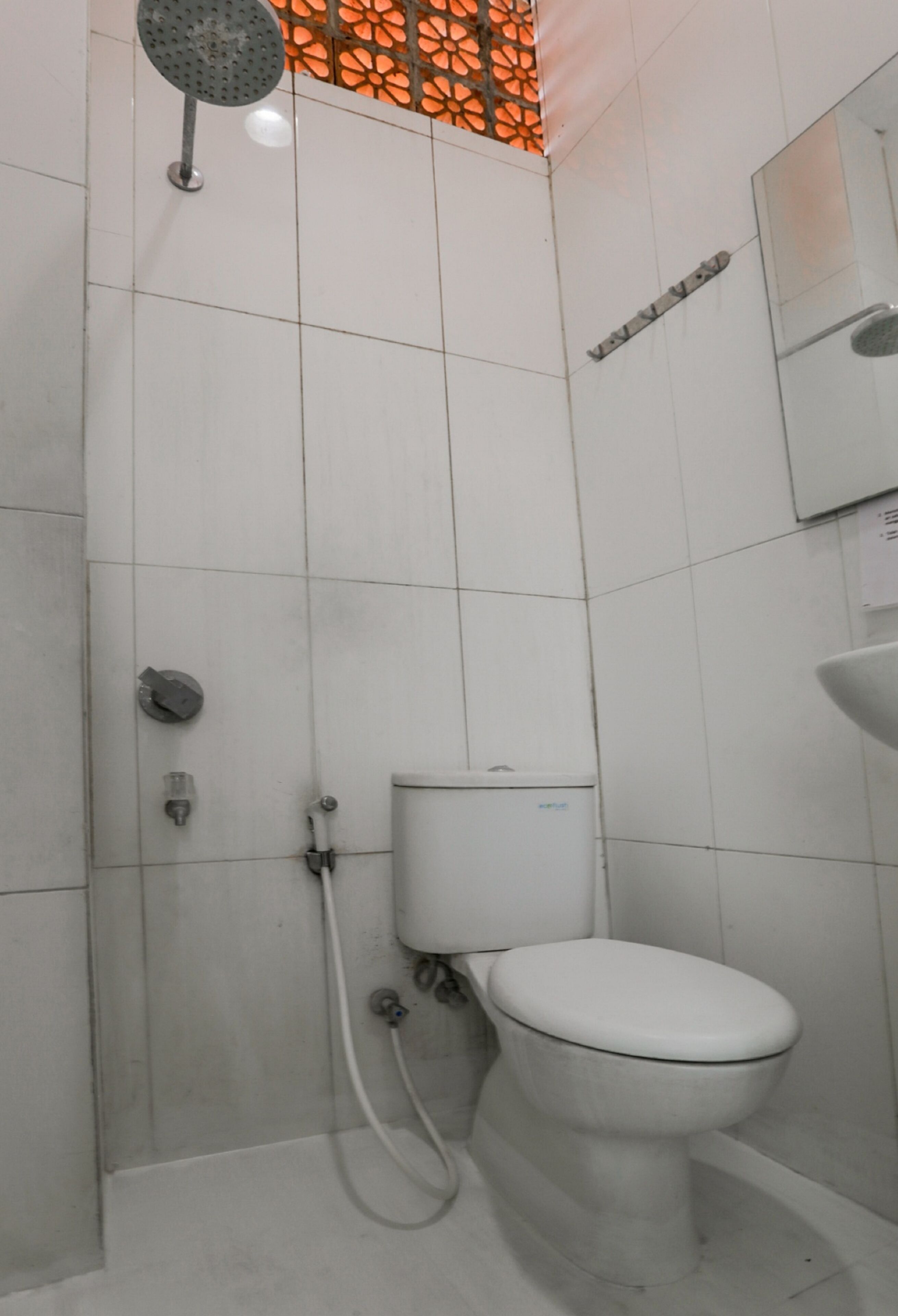 A small, tiled bathroom with a toilet, a shower, and a sink.
