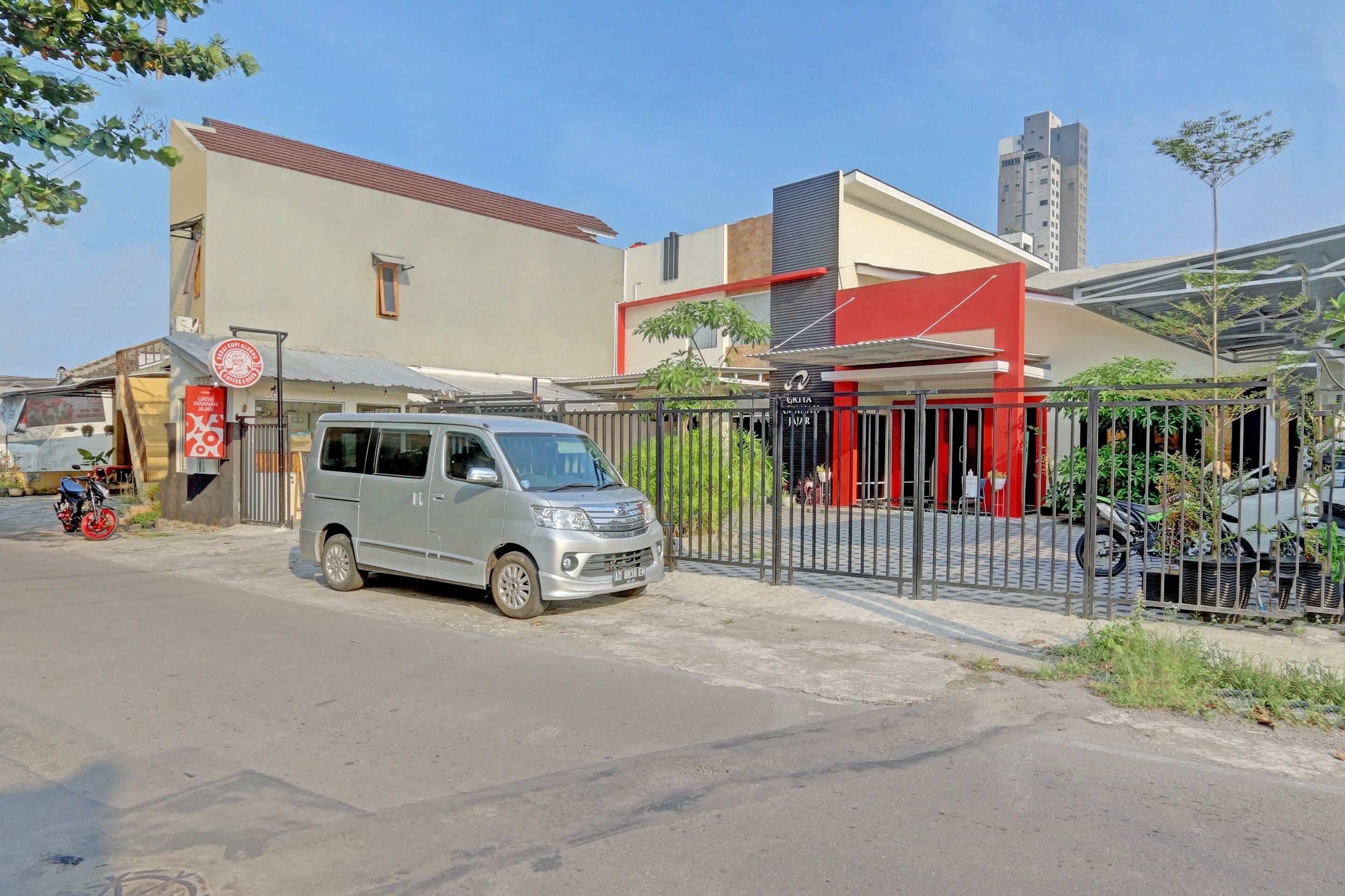 A building with a gated entrance, a parked van, and a motorcycle.