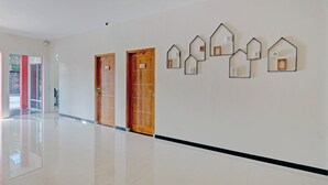 A hallway with polished tile flooring, wooden doors, and wall-mounted decorative mirrors.