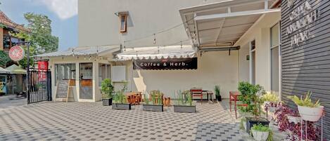 A coffee shop with outdoor seating and potted plants.