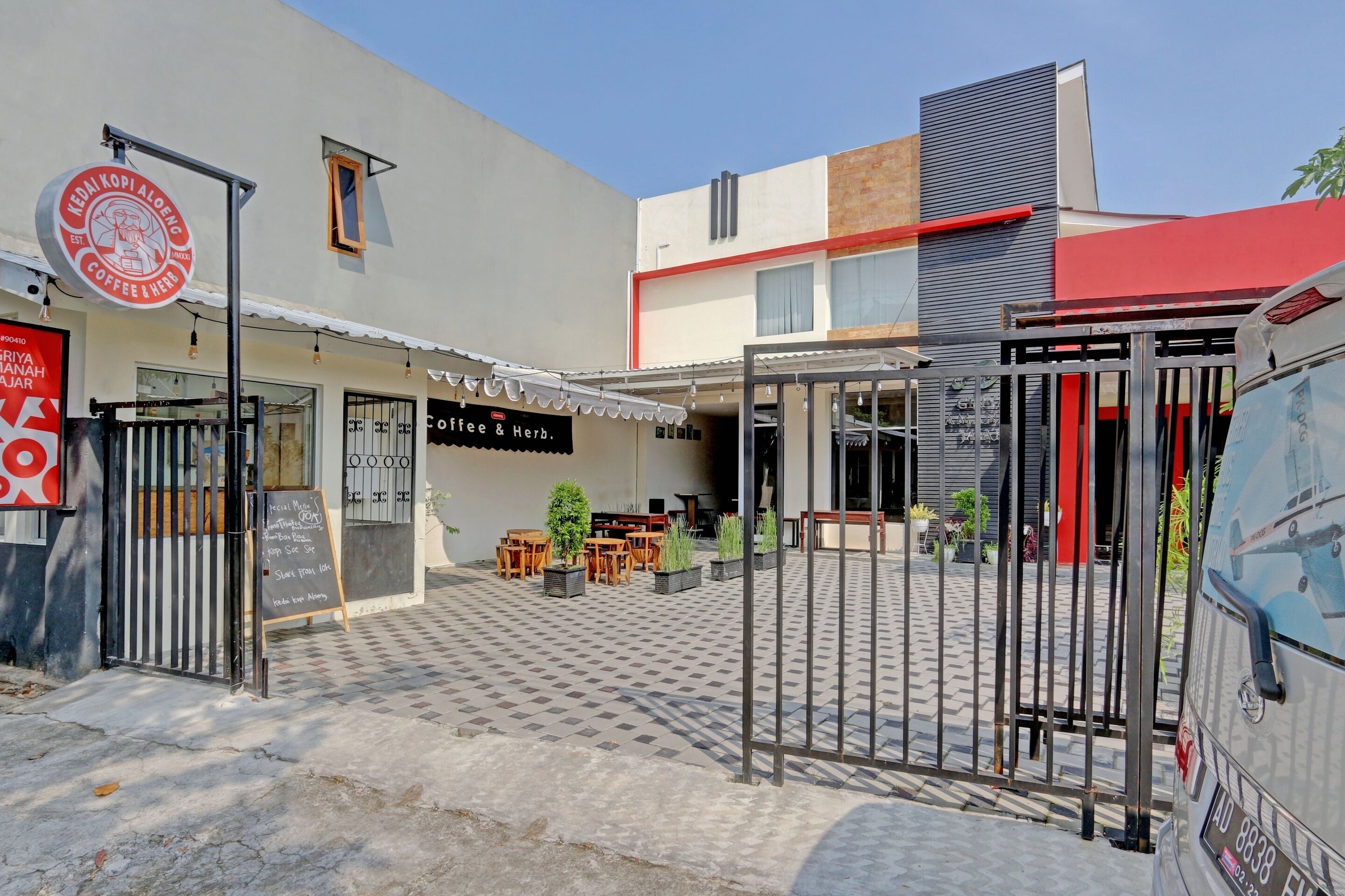 Una cafetería con terraza, un cartel y una entrada con reja.