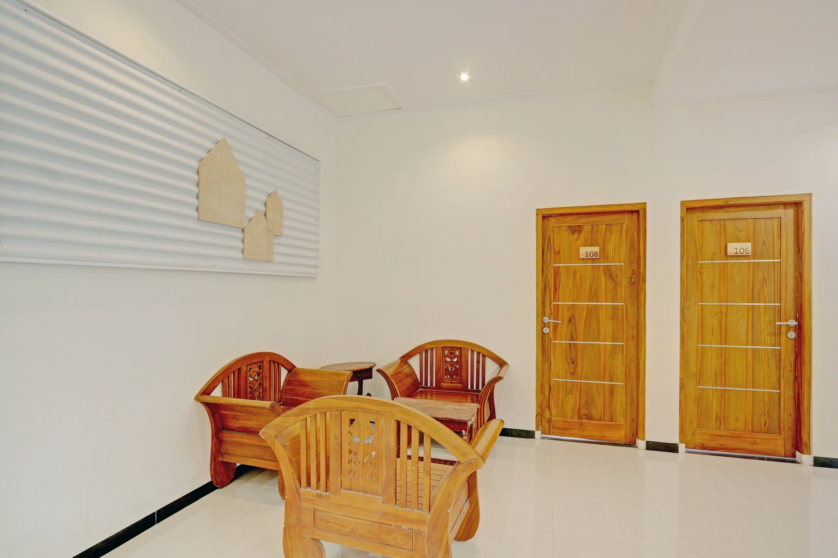 A hotel lobby with wooden furniture, two wooden doors labeled 108 and 106, and a wall-mounted artwork.