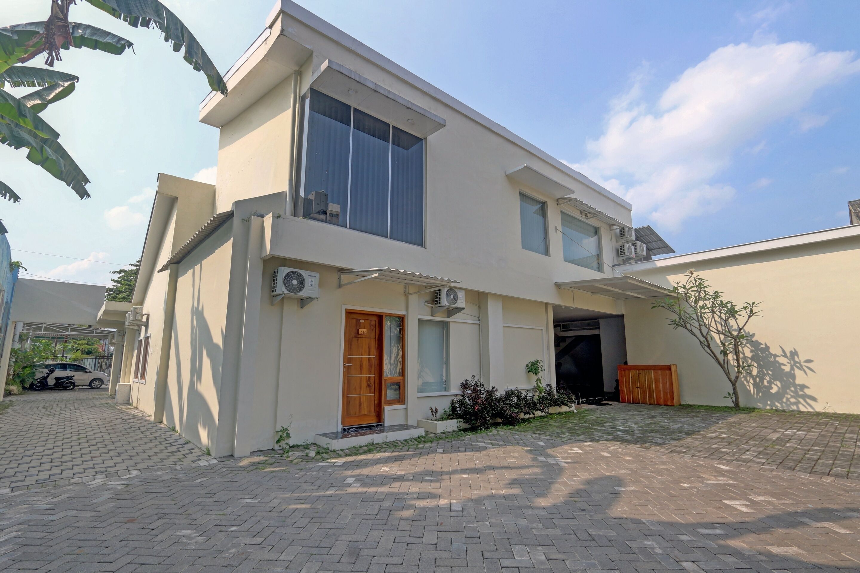 A two-story building with a modern design, featuring a large window on the upper floor and a wooden door on the ground floor.