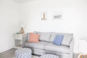A neutral-colored sofa with patterned cushions, a small side table with a lamp, and a framed picture on the wall. - Central Location l Steps from Ocean l Top Floor (Myrtle Beach)