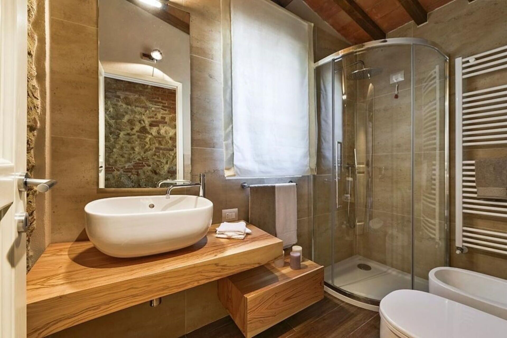 Un baño moderno con un lavamanos grande, cabina de ducha y un inodoro.