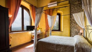 A bedroom with a bed, a desk, and a window with curtains.