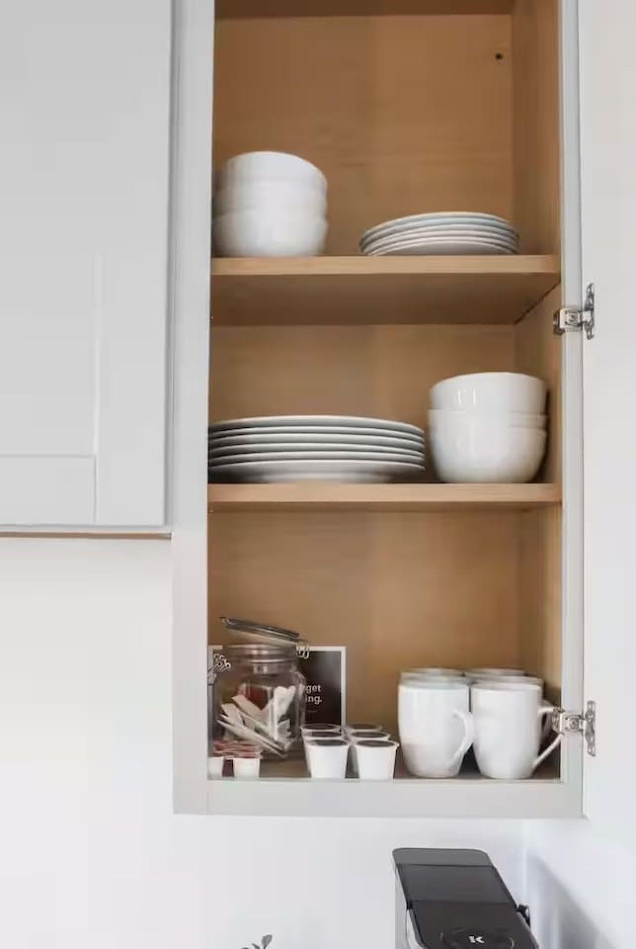 A kitchen cabinet with shelves holding plates, bowls, and cups.
