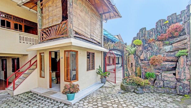 Un hôtel au design traditionnel, doté d’un balcon en bois, d’une porte rouge et d’un jardin de rocaille.