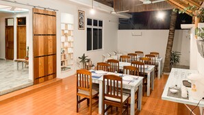 A dining area with wooden tables and chairs, a ceiling fan, and a staircase leading to an upper level. - FINS DIVE AND LEISURE HOTEL (Rasdhoo)