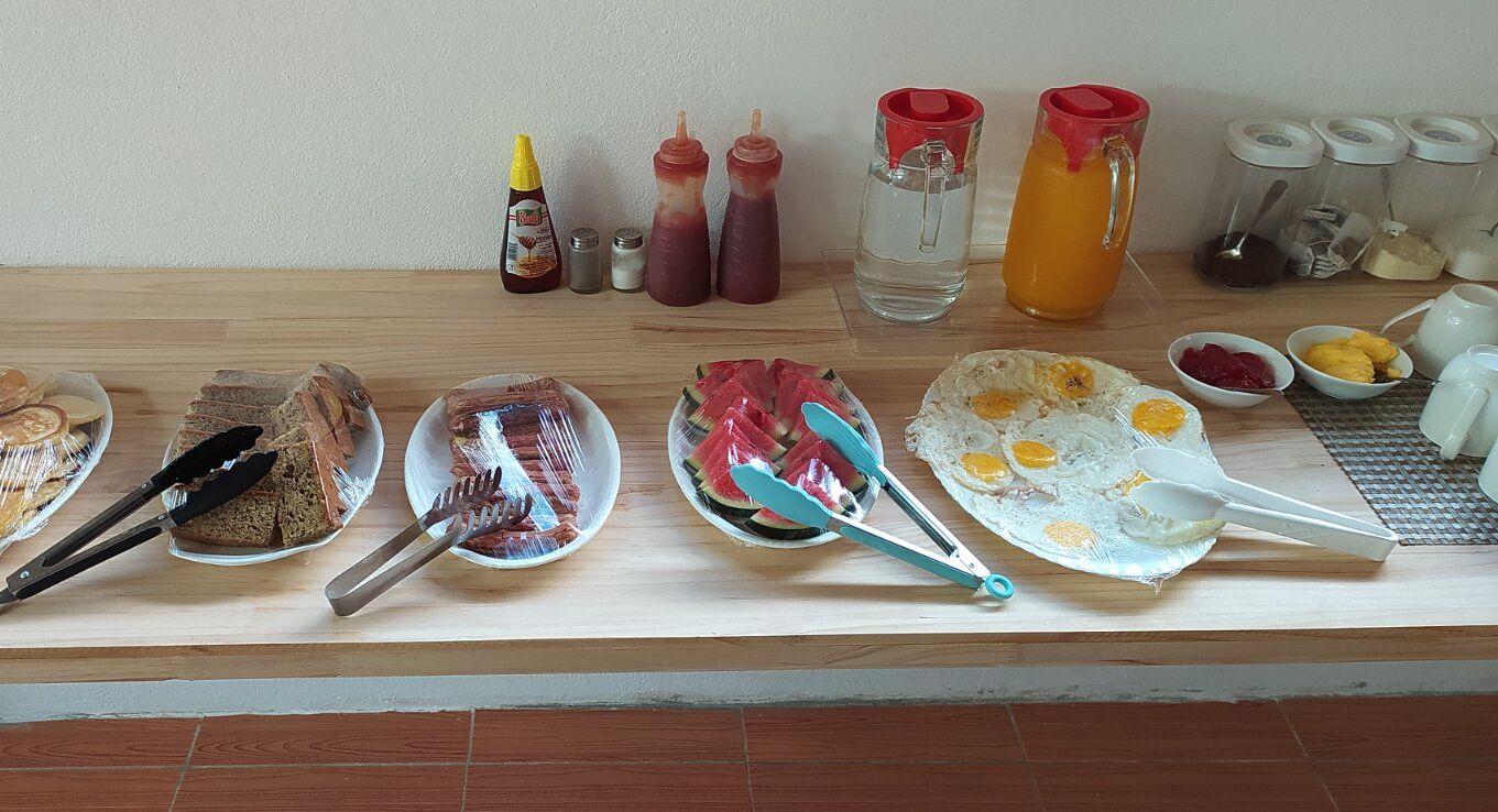 A breakfast setup with various food items and condiments on a wooden table.