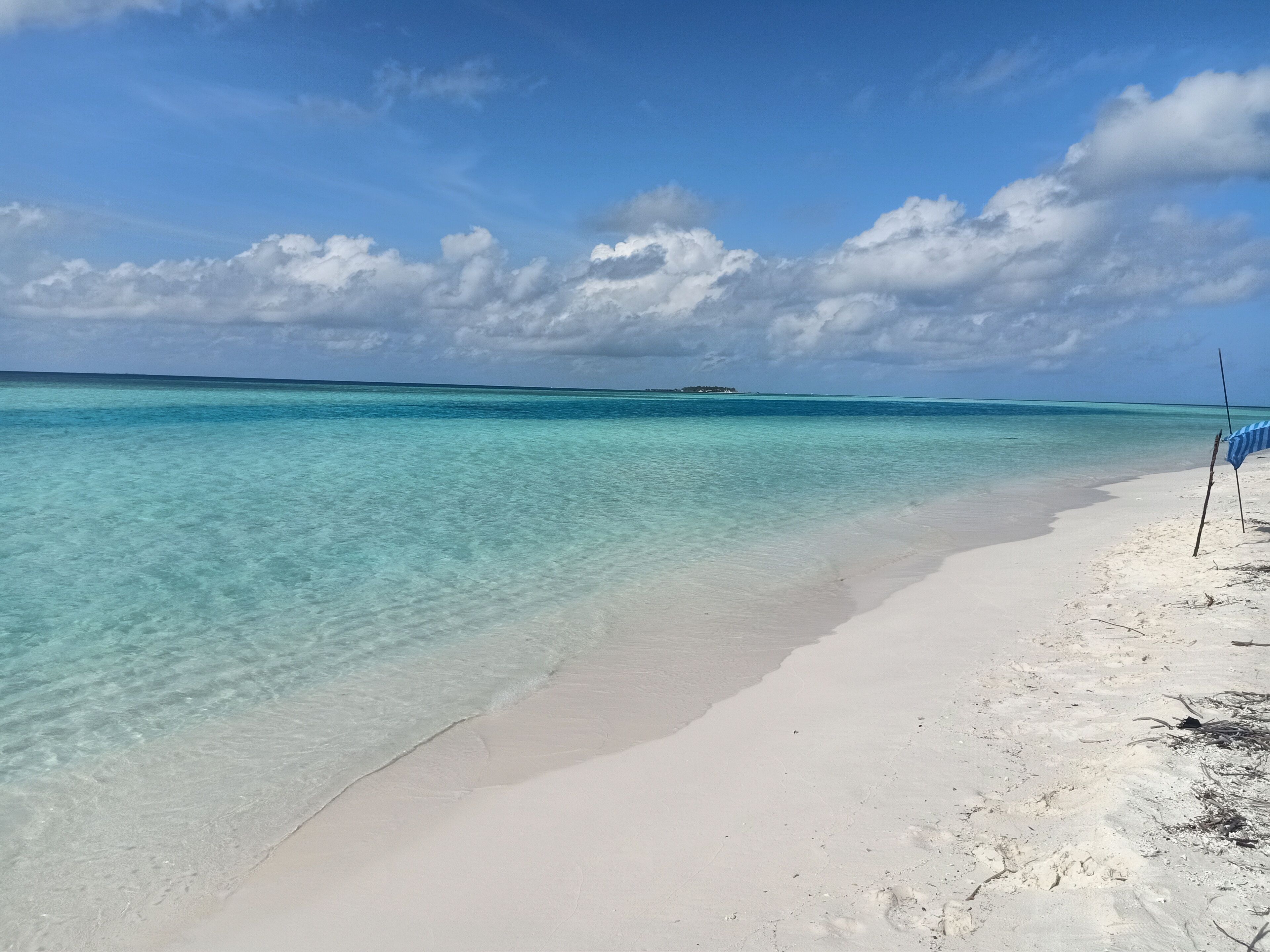 Une plage à l’eau turquoise et limpide, bordée d’un rivage sablonneux.