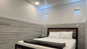 Une chambre moderne avec une tête de lit en bois, un lit bien fait avec du linge de lit blanc, et deux appliques murales.