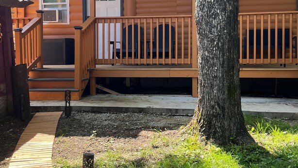 Une cabane en bois dotée d’une terrasse, d’un escalier et d’un petit porche.