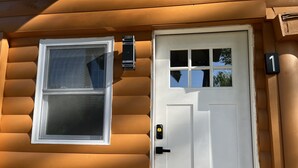 Une cabane en rondins avec une porte blanche et une fenêtre.