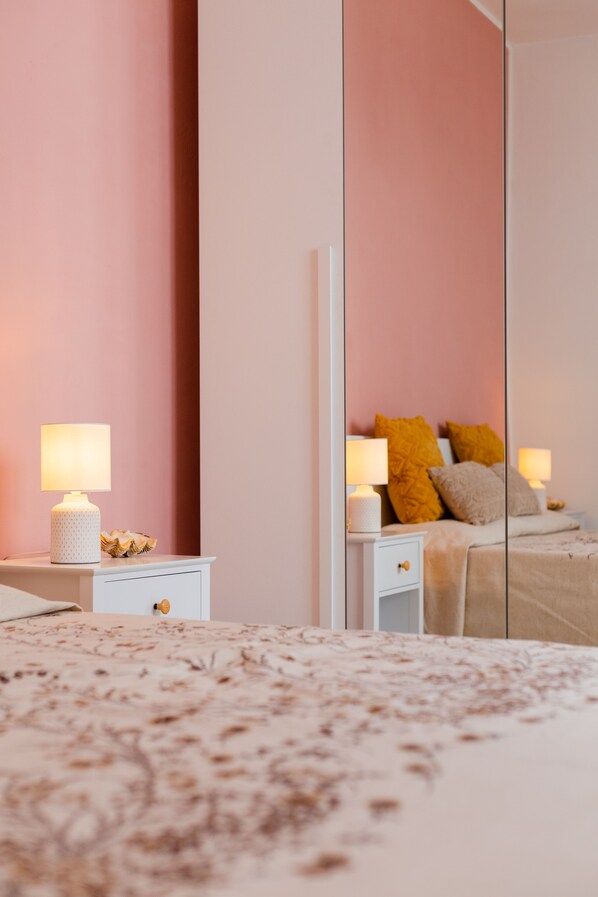 A bedroom with a bed, a nightstand, a lamp, and a mirror. - Nonna Angelina Vacation Home (Sant'Antioco)