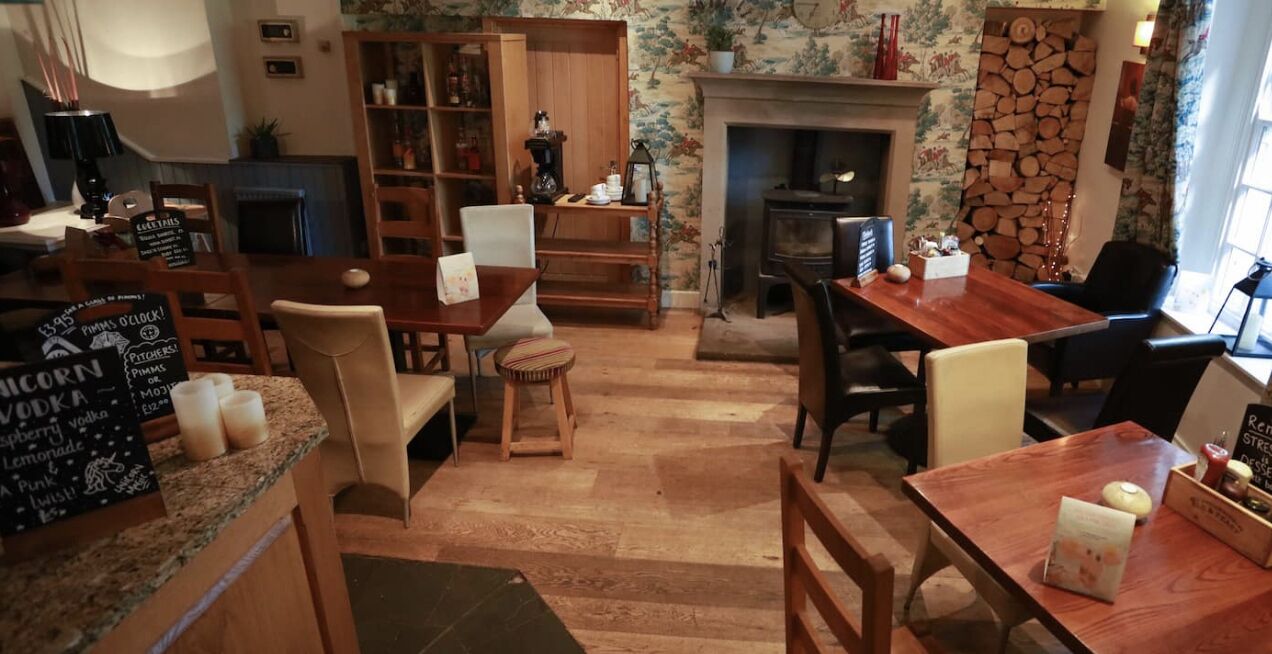 A cozy, well-lit room with a fireplace, wooden furniture, and a bookshelf.